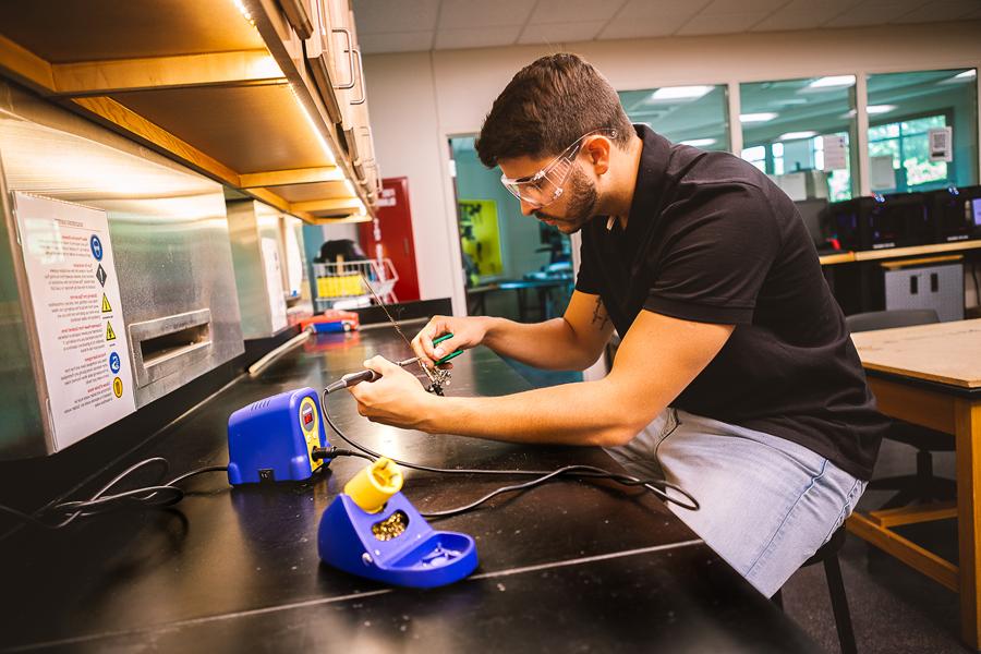 恩里克戴安娜, a senior completing his degree in 澳门威尼斯人网址’s Bachelor of Science 工程专业, fixes up the solder on a radio antenna used as part of a summer re搜索 project.